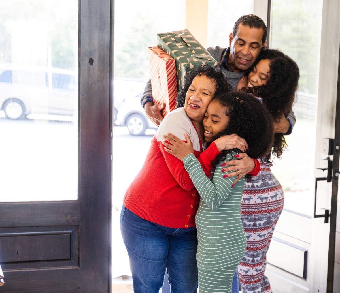 Family hugging at doorstep with gifts