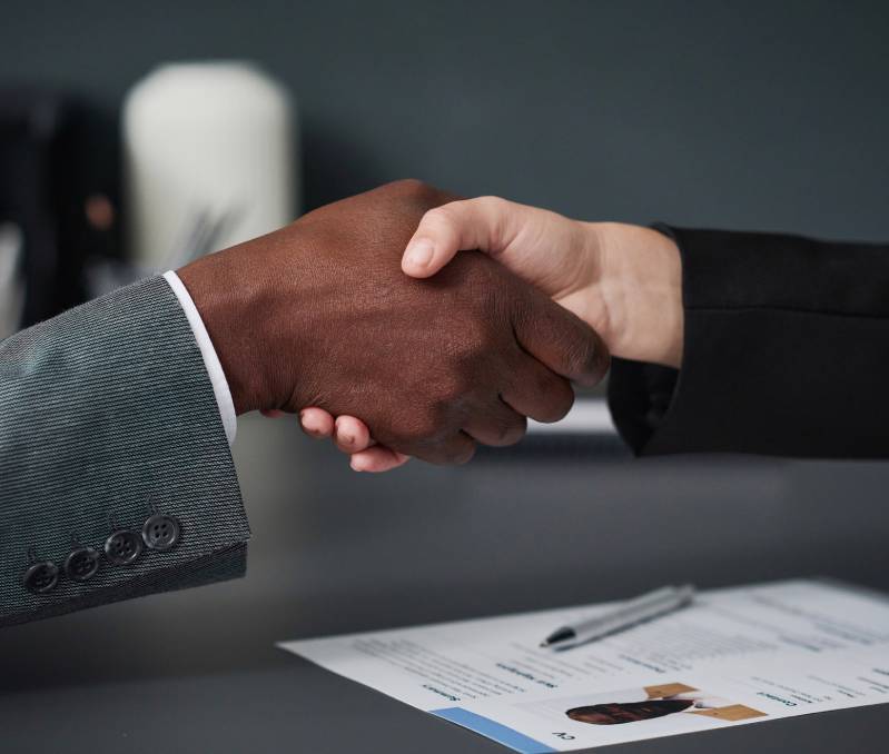 Two people shaking hands over document