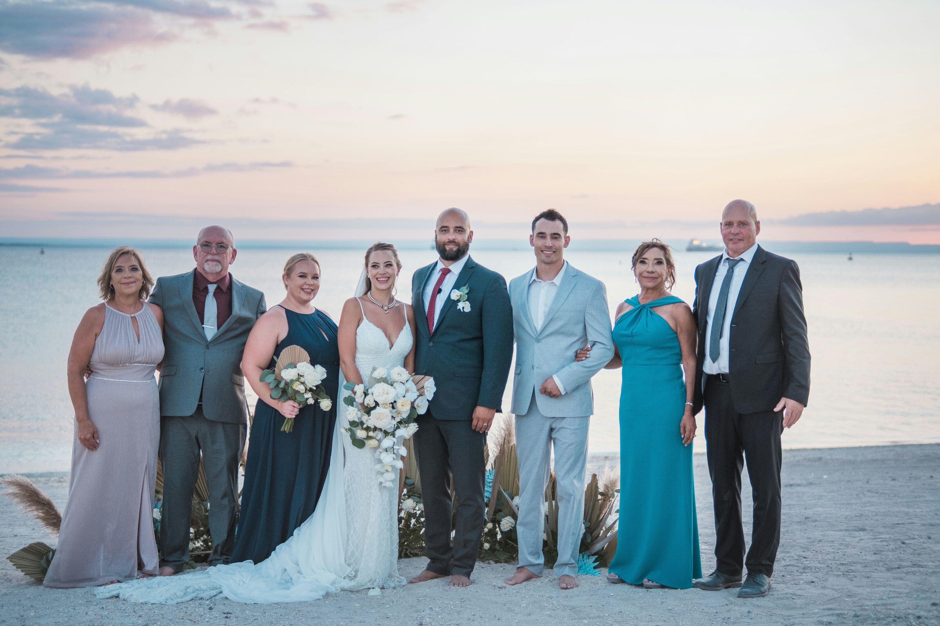 A wedding party posing outdoors at sunset with a scenic backdrop.
